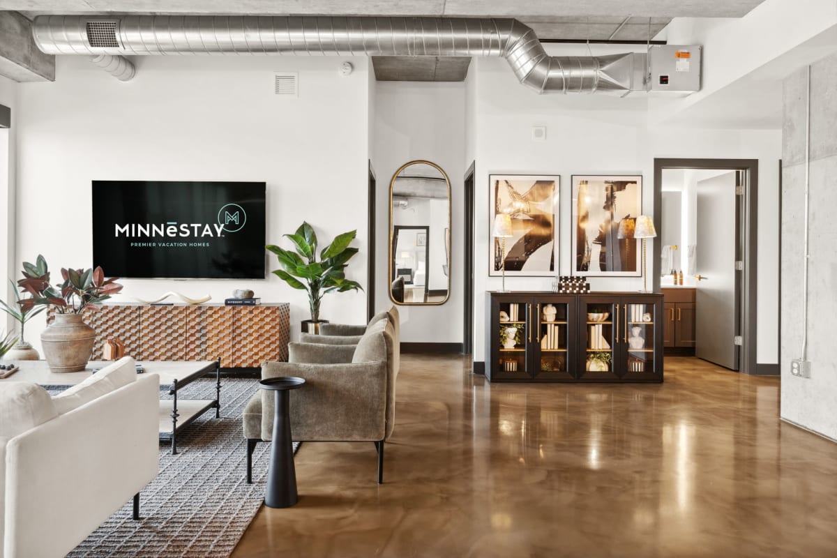 Unwind in your spacious living room featuring polished concrete floors, exposed ductwork, and a cozy seating area with modern furnishings.