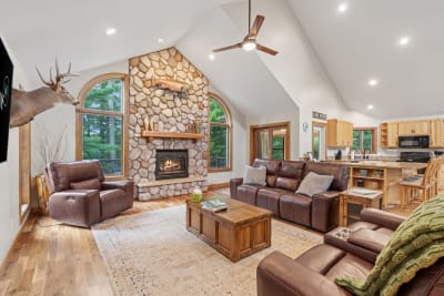 A spacious and inviting living room with a stone fireplace, leather sofas, and natural light.