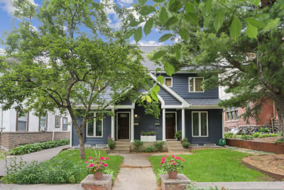Front view of a stylish duplex with a blue exterior and flower pots.