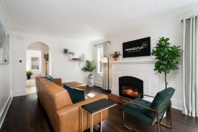 A cozy living room with a leather sofa, brick fireplace, and modern decor.