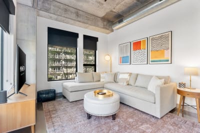 Contemporary living room with sectional sofa, abstract art, and polished concrete flooring.