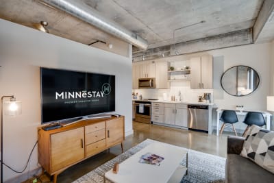 Modern living space of a vacation rental featuring a TV, kitchen, and cozy seating area.