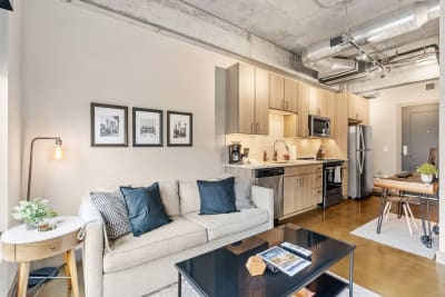 A stylish studio apartment featuring a sofa, kitchen, and dining space.