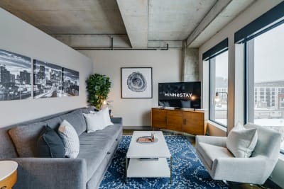 Stylish contemporary living room featuring a gray sofa, white coffee table, and large windows.