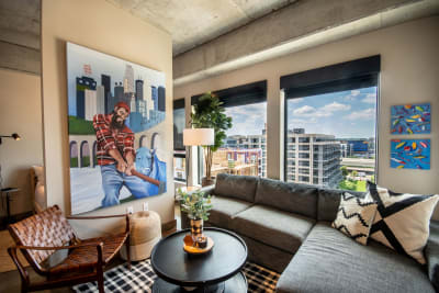 Modern living room with a colorful mural, gray sofa, and urban skyline view.