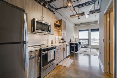 Stylish kitchen with stainless steel appliances and a cozy living area in the background.