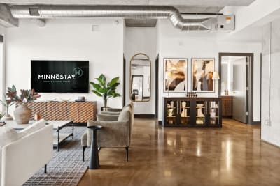 Chic modern living room with a large TV, cozy seating, and decorative plants.