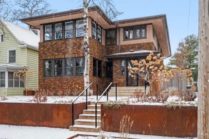 A modern brick house in winter with snow and dried plants.