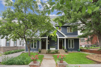 Front view of a stylish duplex with a blue exterior and flower pots.