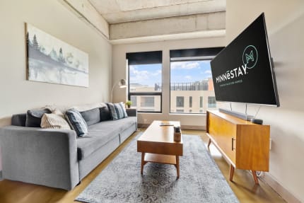 Contemporary living room with a gray sofa, wooden coffee table, and large windows.