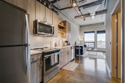 Stylish kitchen with stainless steel appliances and a cozy living area in the background.