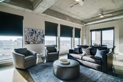 Modern living room featuring exposed concrete ceiling, large windows, and contemporary furniture.