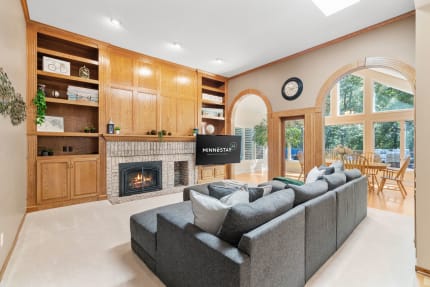 Cozy living room with a gray sofa and brick fireplace, featuring arched windows and oak cabinetry.