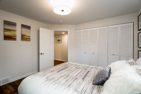 A cozy bedroom featuring a bed with textured bedding, abstract wall art, and a built-in closet.