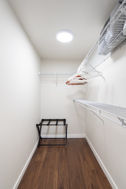 An organized and minimalist closet space with wire shelves and a black stool.
