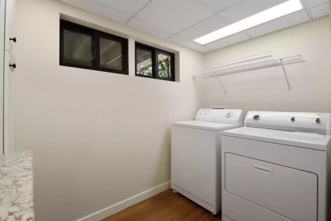 A clean laundry room featuring a washing machine, dryer, and a window.