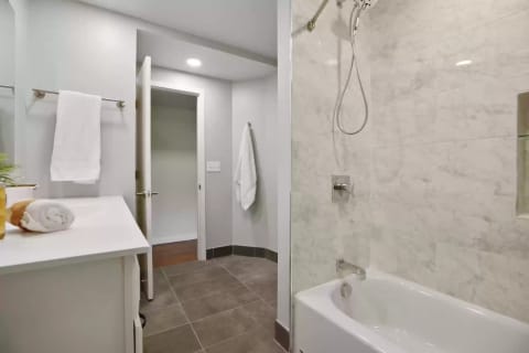 Contemporary bathroom featuring a shower, tub, and white towels.