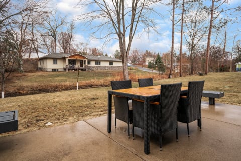 Outdoor dining set on a patio with a view of a house and lawn.