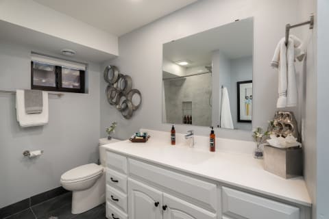Modern bathroom with gray walls, white vanity, and decorative elements.