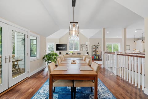 A modern dining area featuring a wooden table and beige chairs, illuminated by a pendant light.