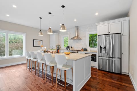 Modern kitchen featuring a spacious island, white bar stools, and stainless steel appliances.
