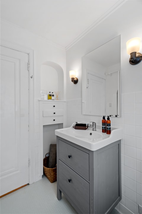 A neat bathroom featuring a gray vanity, mirror, and organized toiletries.