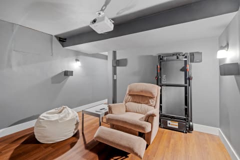 A home theater room featuring a beige recliner, bean bag chair, and projector.