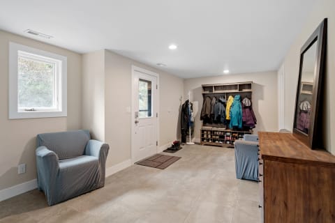 An organized entryway with a chair, storage for coats and shoes, and natural light.