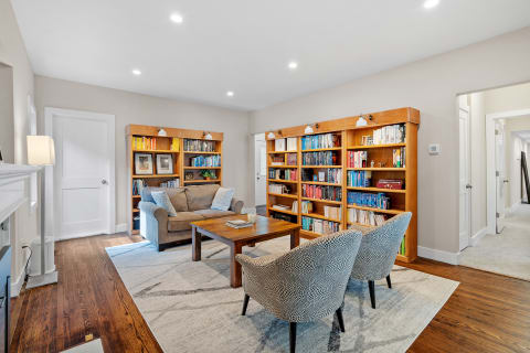Cozy living room featuring a gray sofa, wooden coffee table, and two patterned chairs, with bookshelves filled with books.