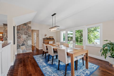 Elegant dining room with wooden table and beige chairs next to large windows.