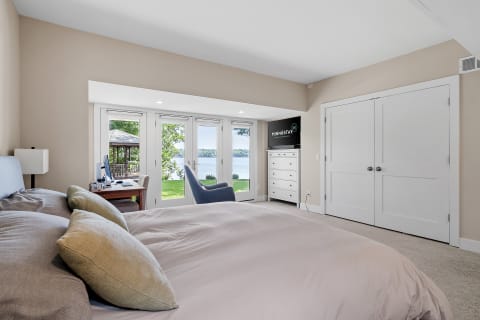 Cozy bedroom overlooking the lake with a desk, armchair, and dresser.