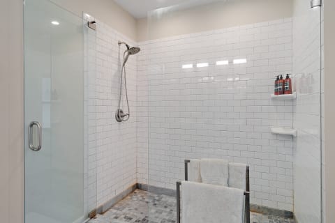 A clean and modern shower area with white subway tiles and a chrome showerhead.