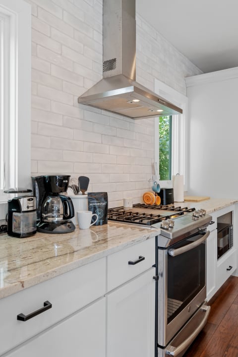 Modern kitchen with white cabinets, granite countertop, and stainless steel appliances.