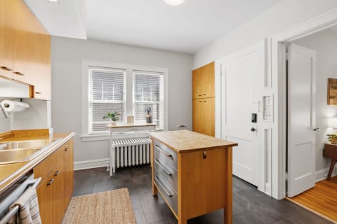 Modern kitchen with wooden cabinets and island, featuring natural light from windows.