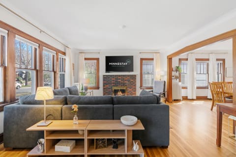 A modern living room with a grey sofa, wooden accents, and large windows.
