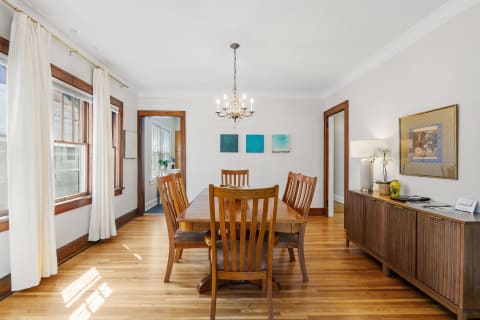 Bright dining room with wooden table, chairs, and decorative elements.
