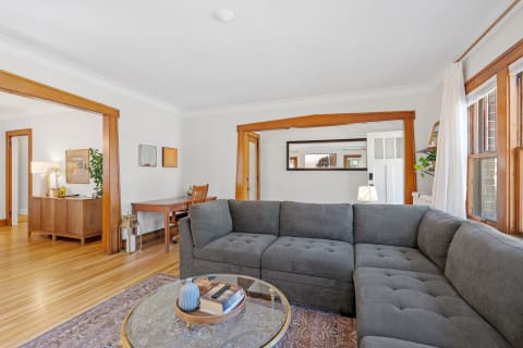 Cozy living room with gray sectional sofa, wooden desk, and natural light.