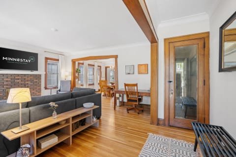 Cozy living room and dining area with gray sofa and wooden furniture.