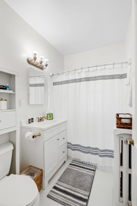 Modern bathroom featuring a white vanity and grey striped shower curtain.
