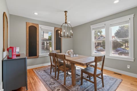 A cozy dining room with a wooden table, chairs, and natural light from windows.