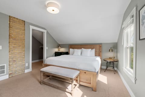 Cozy bedroom featuring a wooden bed, gray walls, and natural lighting.