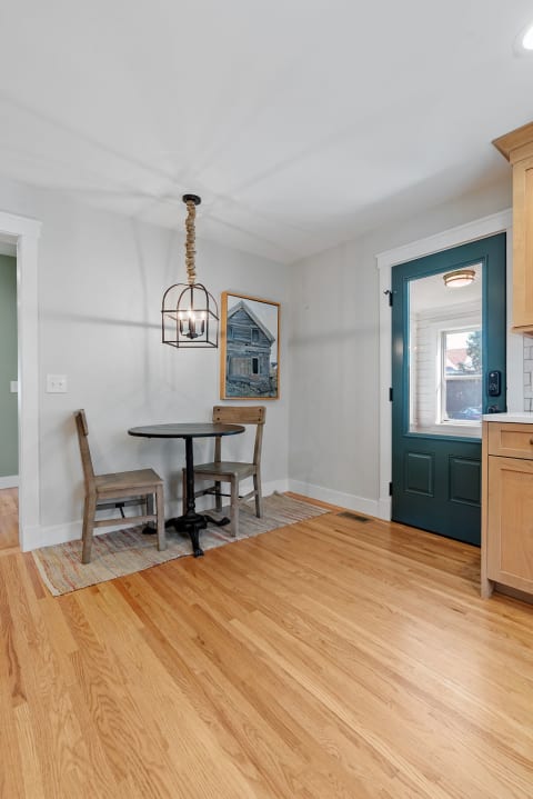 A cozy dining nook with a circular table, two wooden chairs, and a pendant light overhead.