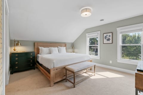 Cozy bedroom with large bed, green dresser, and two windows.