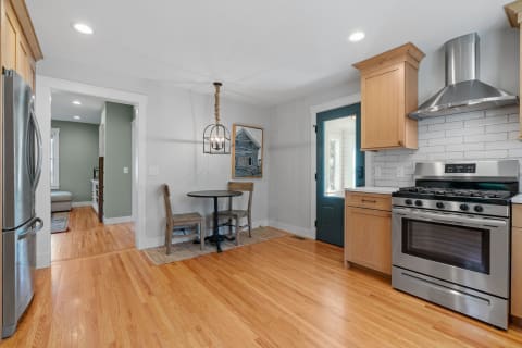 Modern kitchen with wood cabinets, stainless steel stove, and a circular dining table.