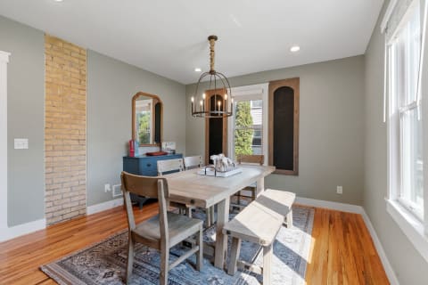 Cozy dining room with wooden furniture, a pendant light, and an exposed brick wall.