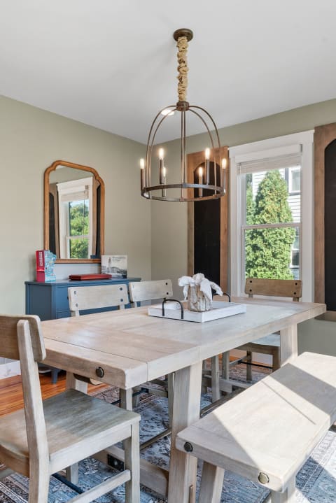 A cozy dining room featuring a wooden table, chairs, and a stylish chandelier.