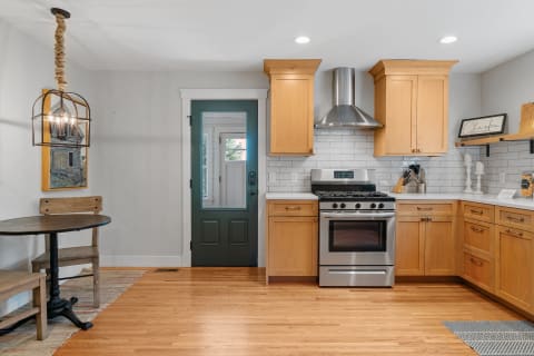 A bright kitchen with wooden cabinets, a black table, and stainless steel appliances.