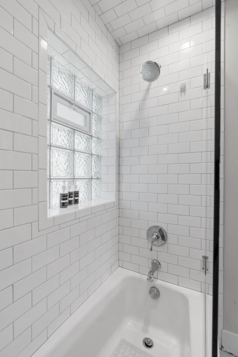 Contemporary shower space featuring white subway tiles and a clear glass enclosure.