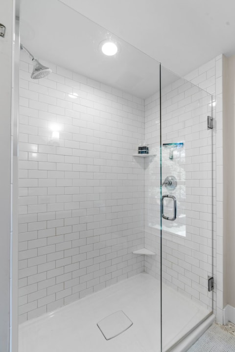 Modern shower with white subway tiles and glass panel.