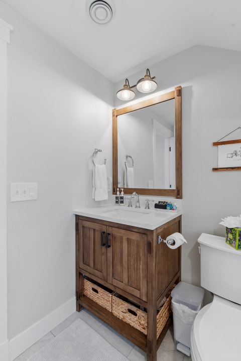 Modern bathroom with a wooden vanity and light fixtures above the mirror.